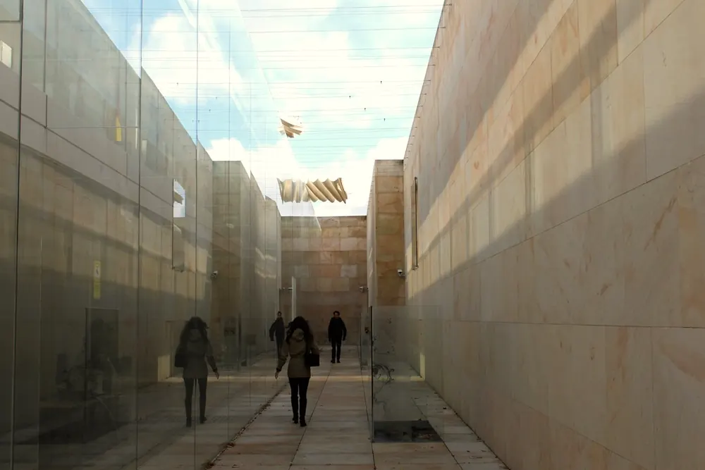 Stone and glass building in Zamora, Spain, with people walking between warm sandstone walls